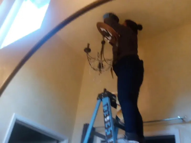 Electrician installing a chandelier in a Palmer residence